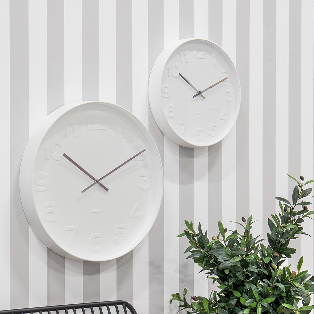 2x Karlsson Mr White Wall Clocks hanging on a striped wall at House