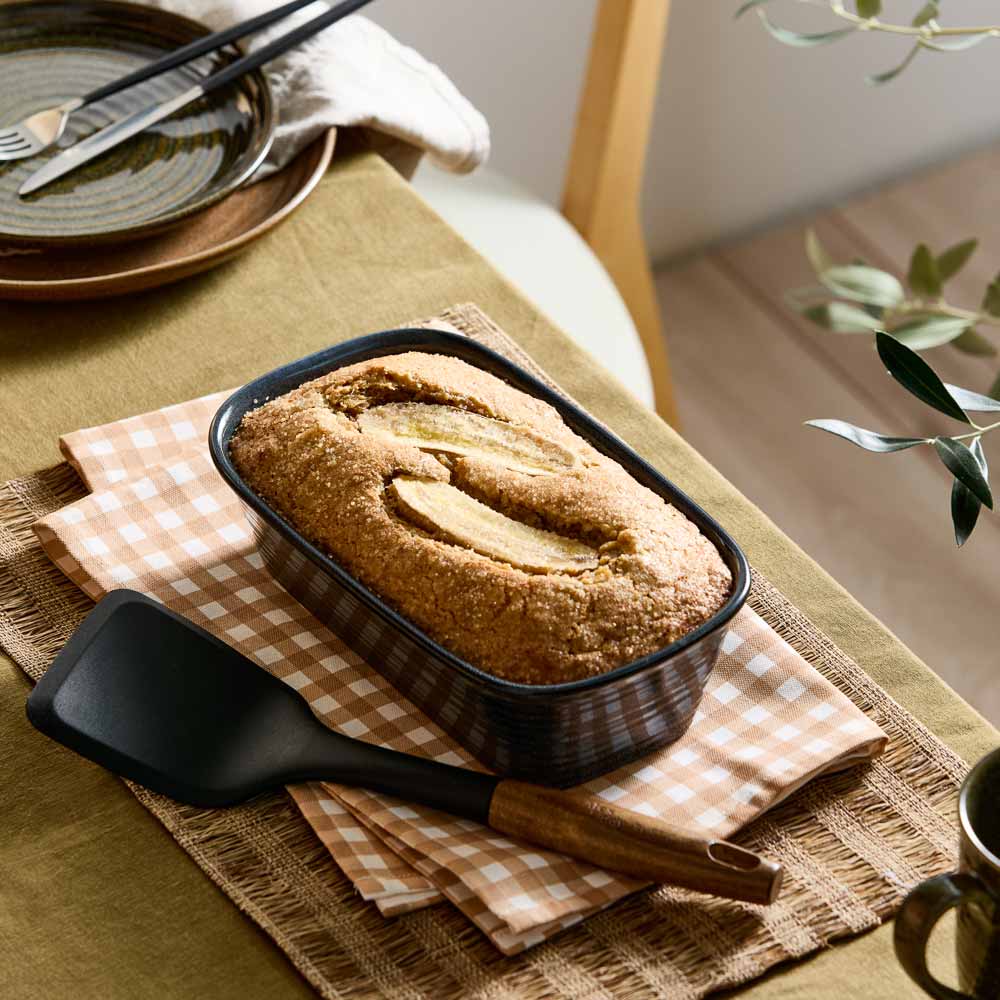 banana bread loaf in a navy blue loaf pan on a table with check tea towel _ House