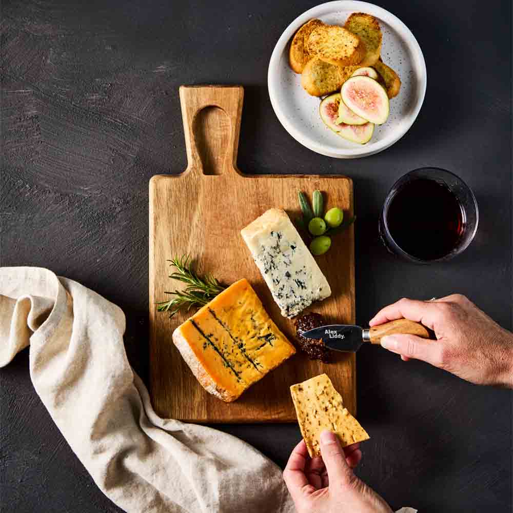 person cutting into quince paste on cheese board with knife - House