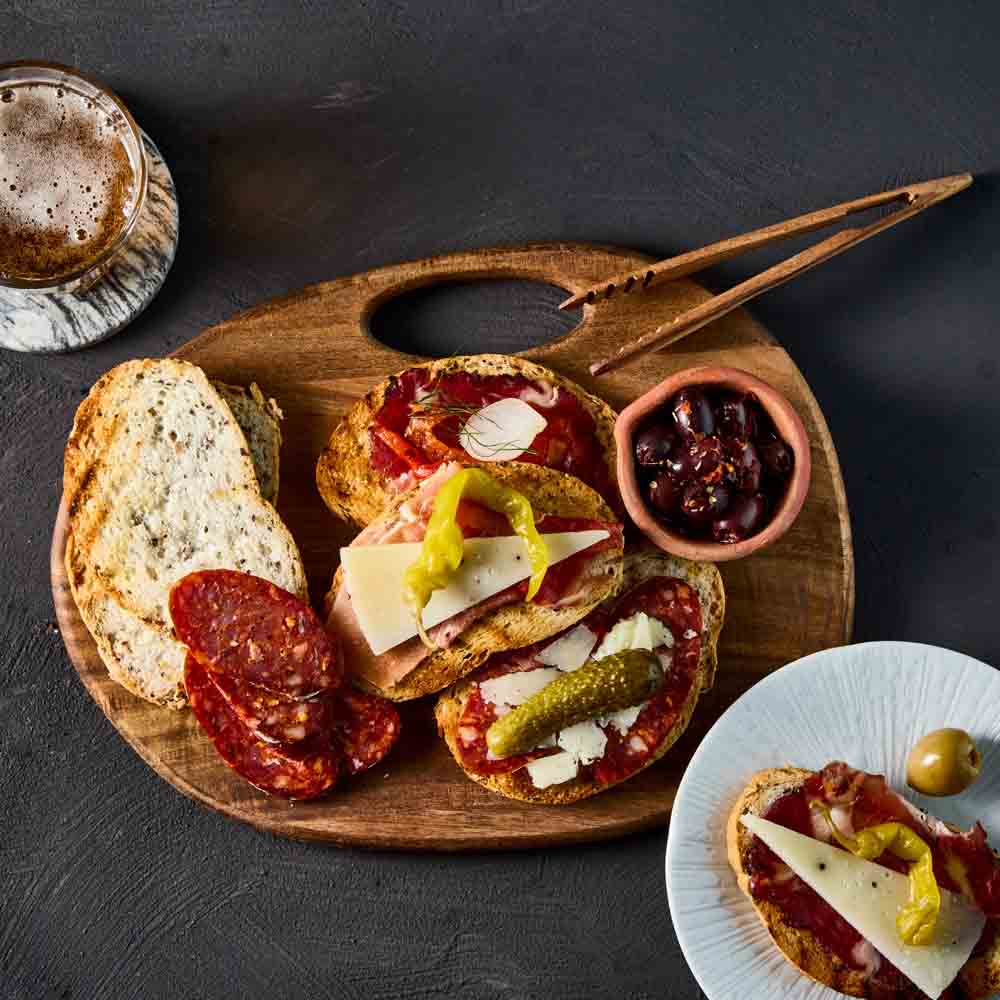 wooden serving board with a sandwich and olives