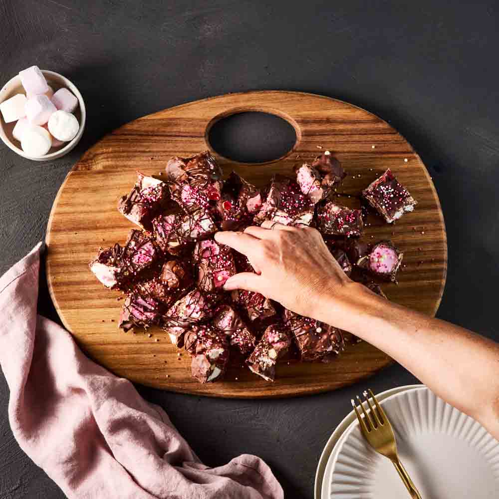 person picking up rocky road from a wooden board