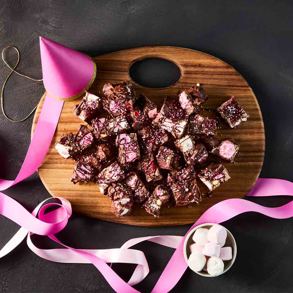 wooden serving board with rocky road and party hat