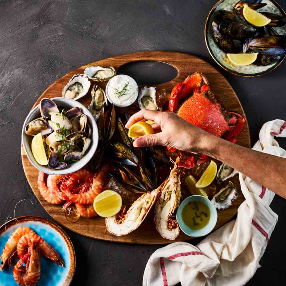 person squeezing lemon onto seafood platter