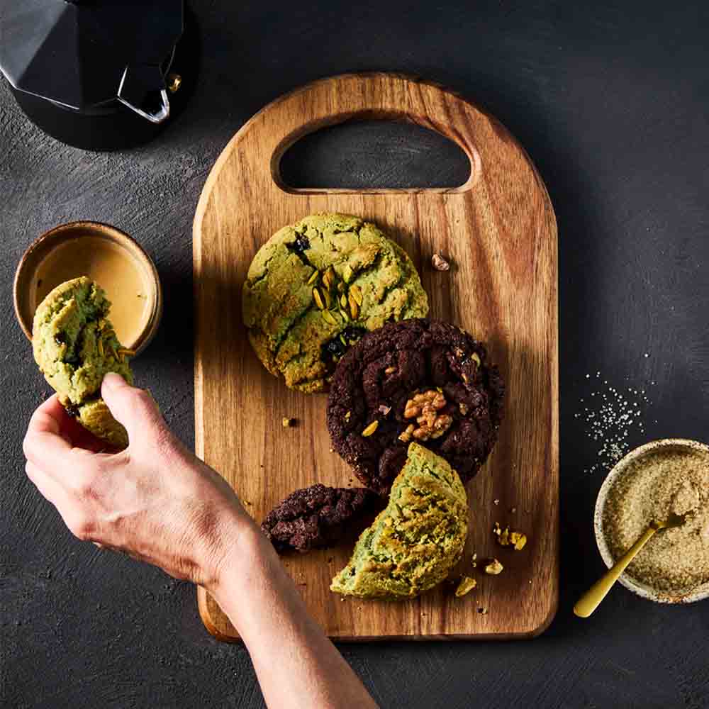 person dipping pistachio cookie into coffee
