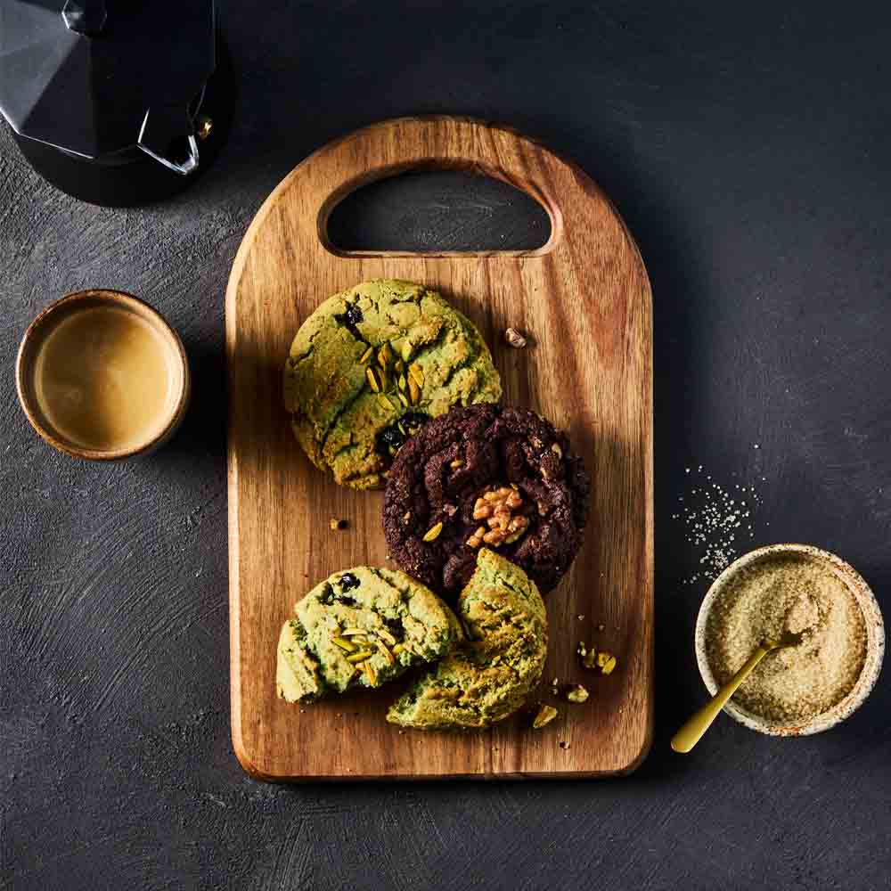 wooden platter of pistachio cookies and chocolate cookie