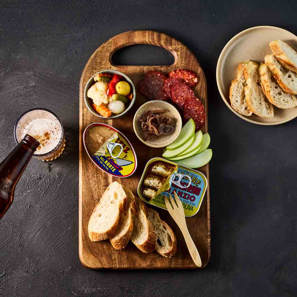 platter of sardines, pate and chorizo on wooden board