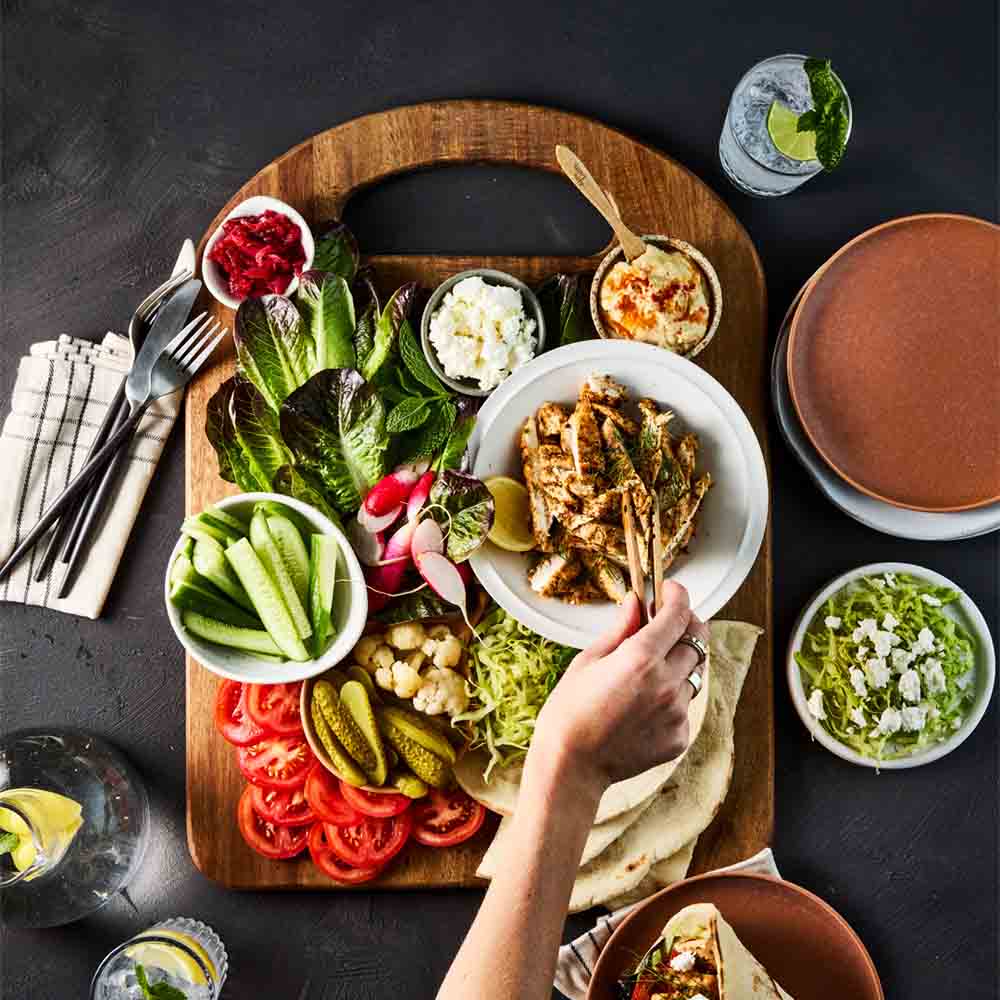 person picking up grilled chicken from a sandwich board