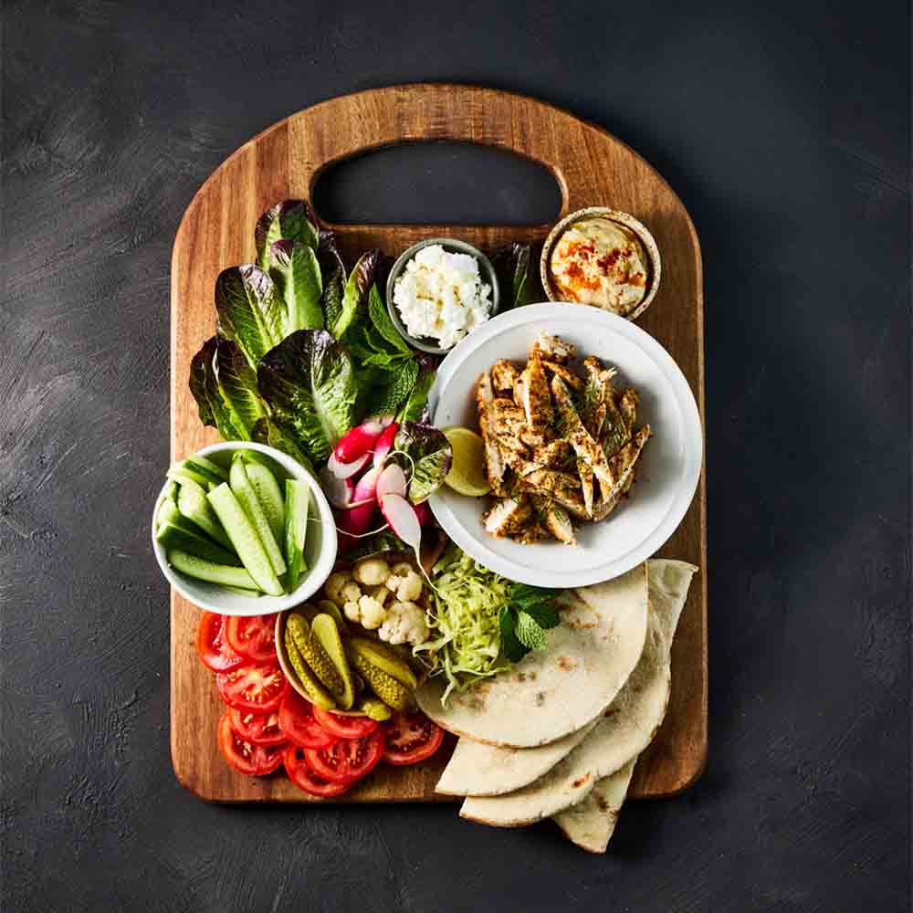 wooden serving board filled with sandwich ingredients