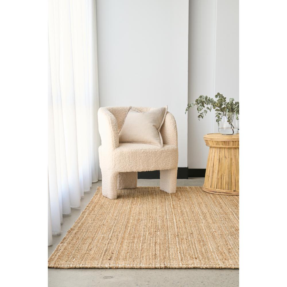 Natural brown jute rug with boucle chair and wicker table - House