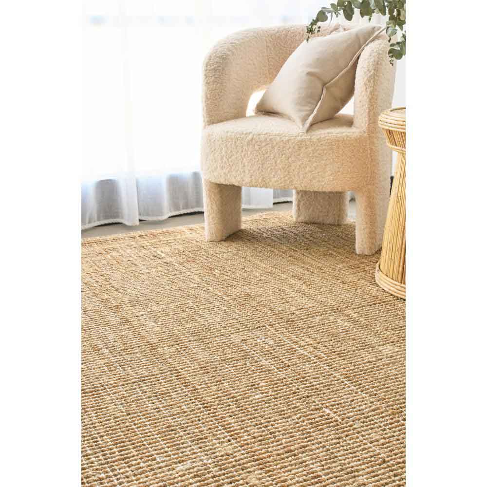 Natural brown jute rug with boucle chair and wicker table - House