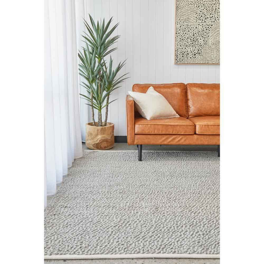 Grey boucle rug with tan leather lounge and plant - House