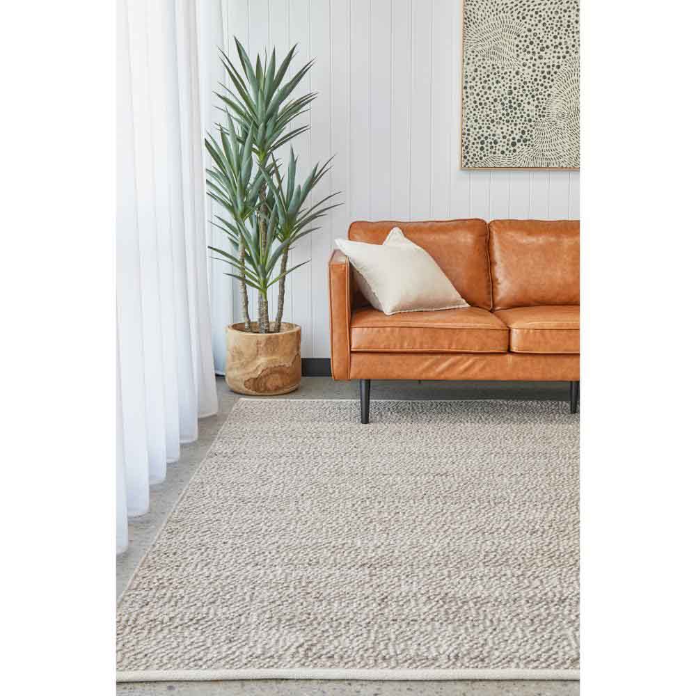 Natural beige boucle rug with tan leather lounge and plant - House