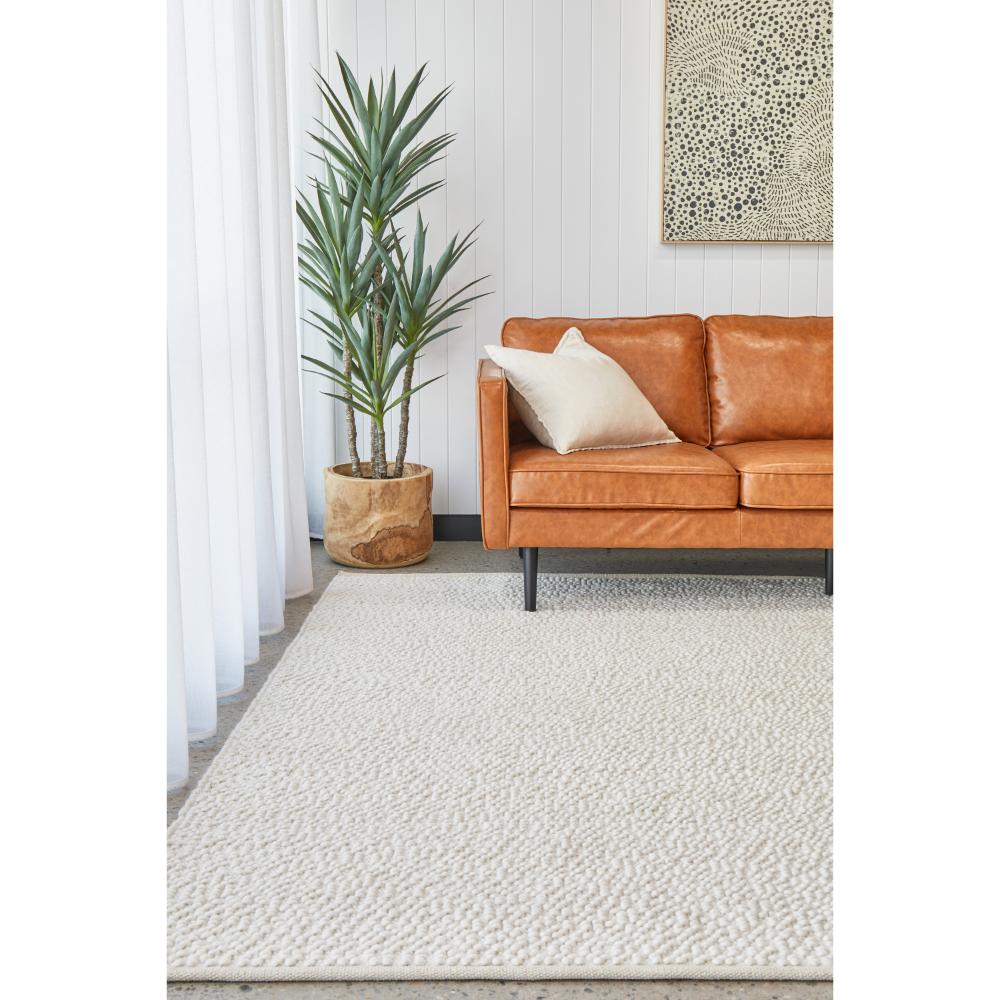 White boucle rug with tan leather lounge and plant - House