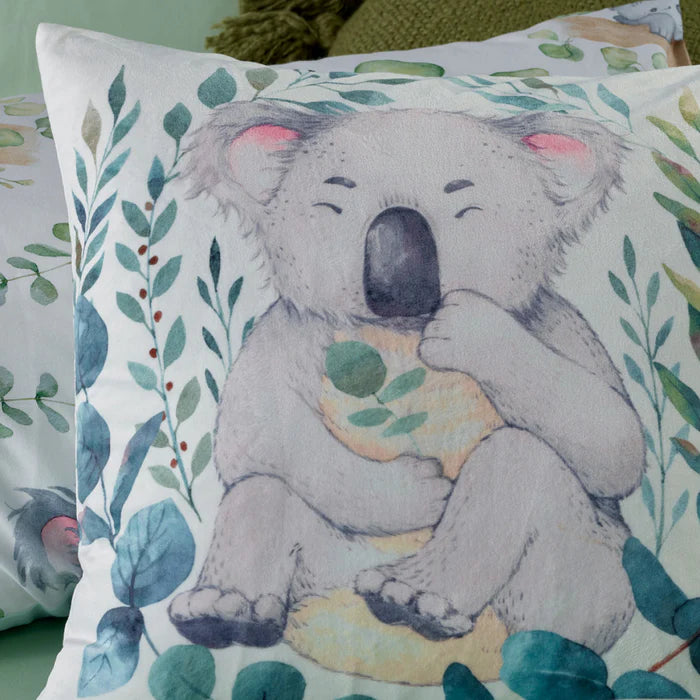 Pillow with a koala design surrounded by leaves on a green background