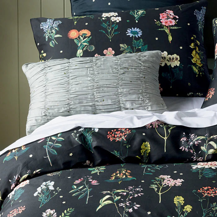 Floral bedding set with dark background and colorful flowers on a bed.