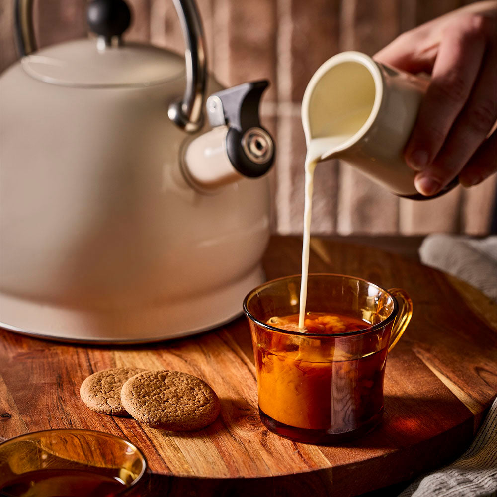 Milk being poured into a cup of tea with the Oat stovetop kettle behind.