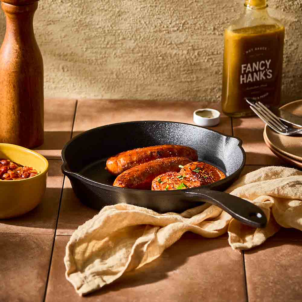 cooked sausages and onions in a cast iron frypan - House