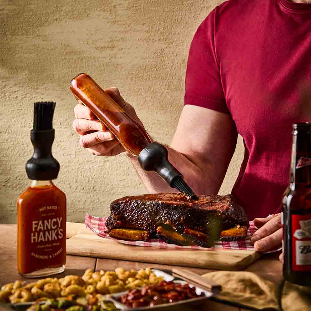 man basting steak with basting bottle cap brush - House