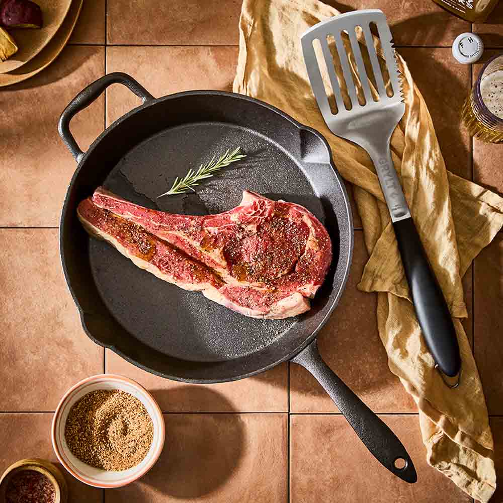 BBQ slotted turner next to cast iron pan with steak - House