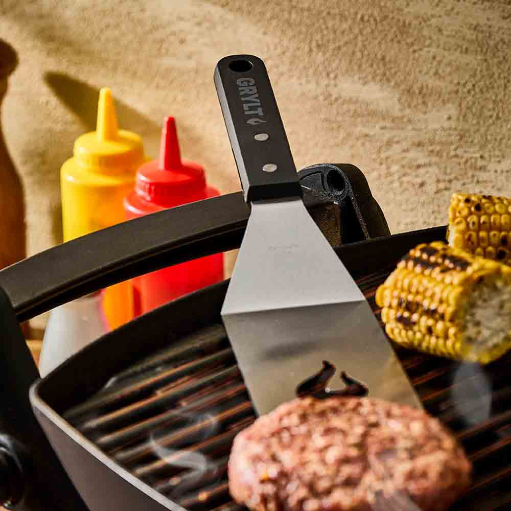slotted griddle spatula turning a burger patty on BBQ - House