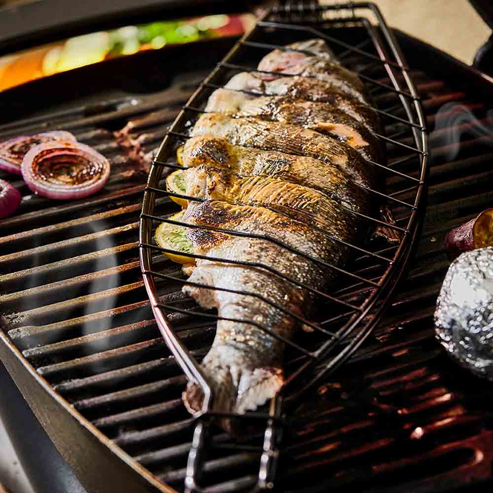 Full fish grilling in a steel fish basket on the BBQ - House