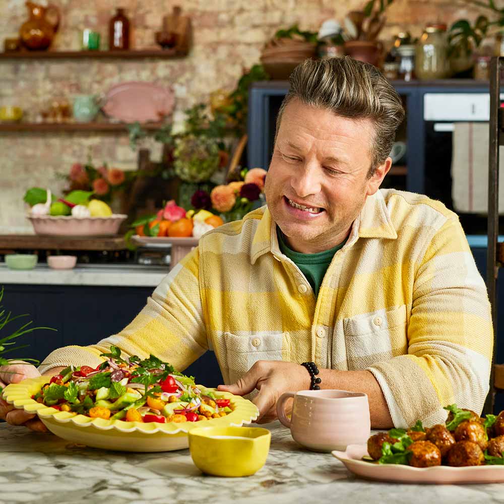 Jamie Oliver holding a large yellow serving bowl full of salad - House