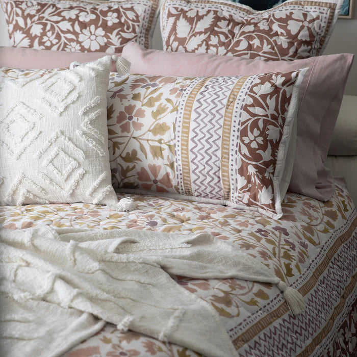 Patterned bedspread with pillows and a blanket on a bed