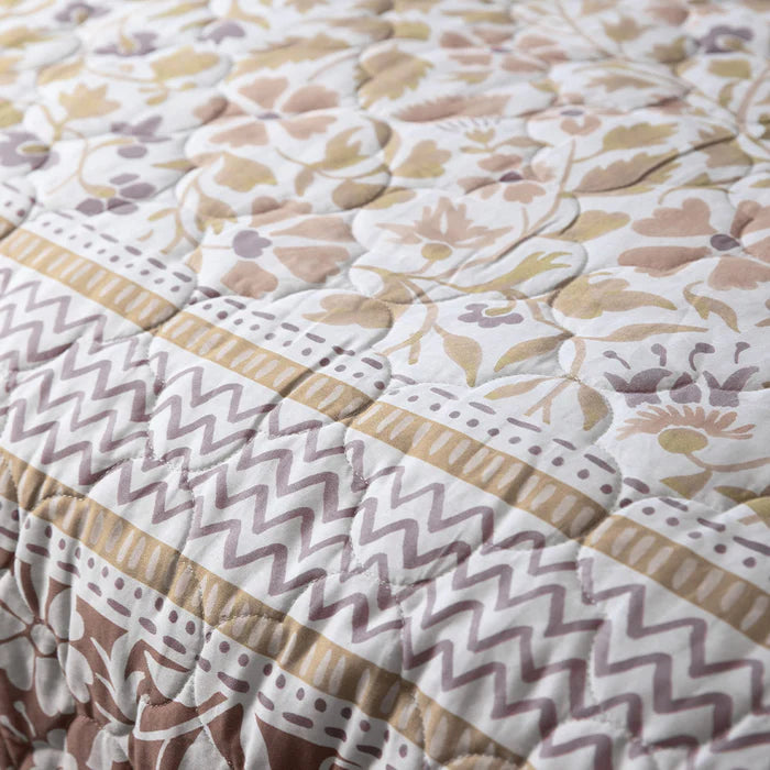 Floral quilt with zigzag border on a white background