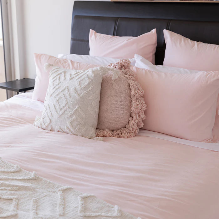 Bed with pink bedding and decorative pillows in a bedroom setting