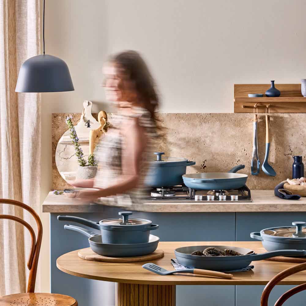 woman walking through a blue theme kitchen