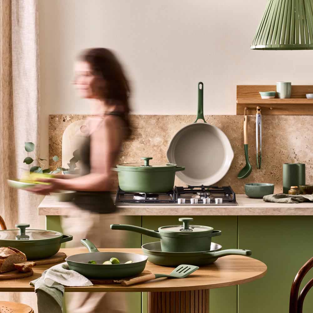 woman walking through a green theme kitchen