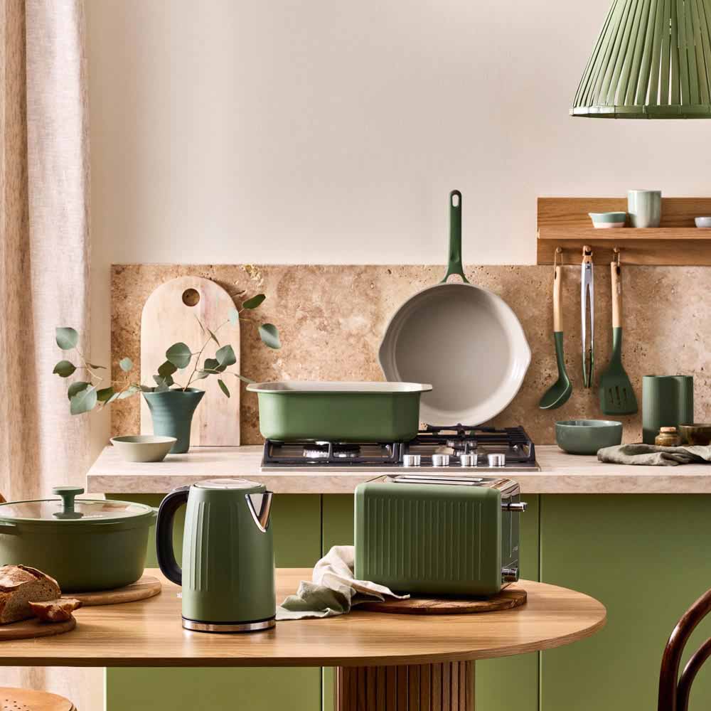 range of green cookware and kettle in a green themed kitchen