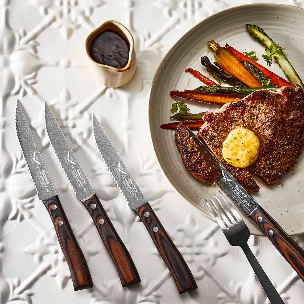 Baccarat Le Connoisseur Steak Knife 4 Piece Set with plate of steak and vegetables on cream ornate tile bench