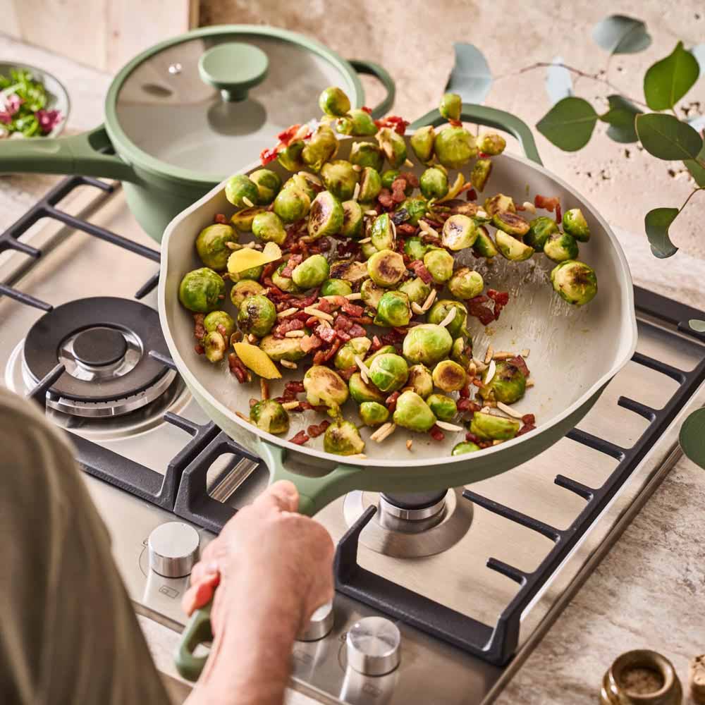 brussell sprouts being tossed in a green frypan