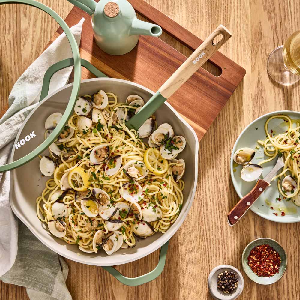 seafood pasta in a green saute pan with spouts