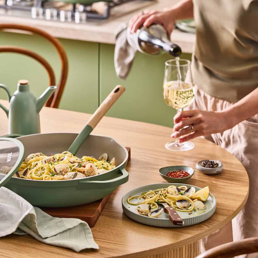 seafood pasta in a green saute pan with spouts