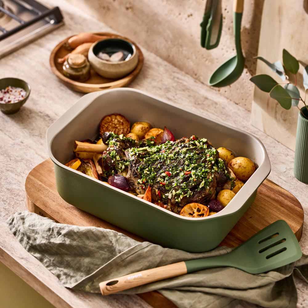 lamb shank and vegetables in a green roasting pan