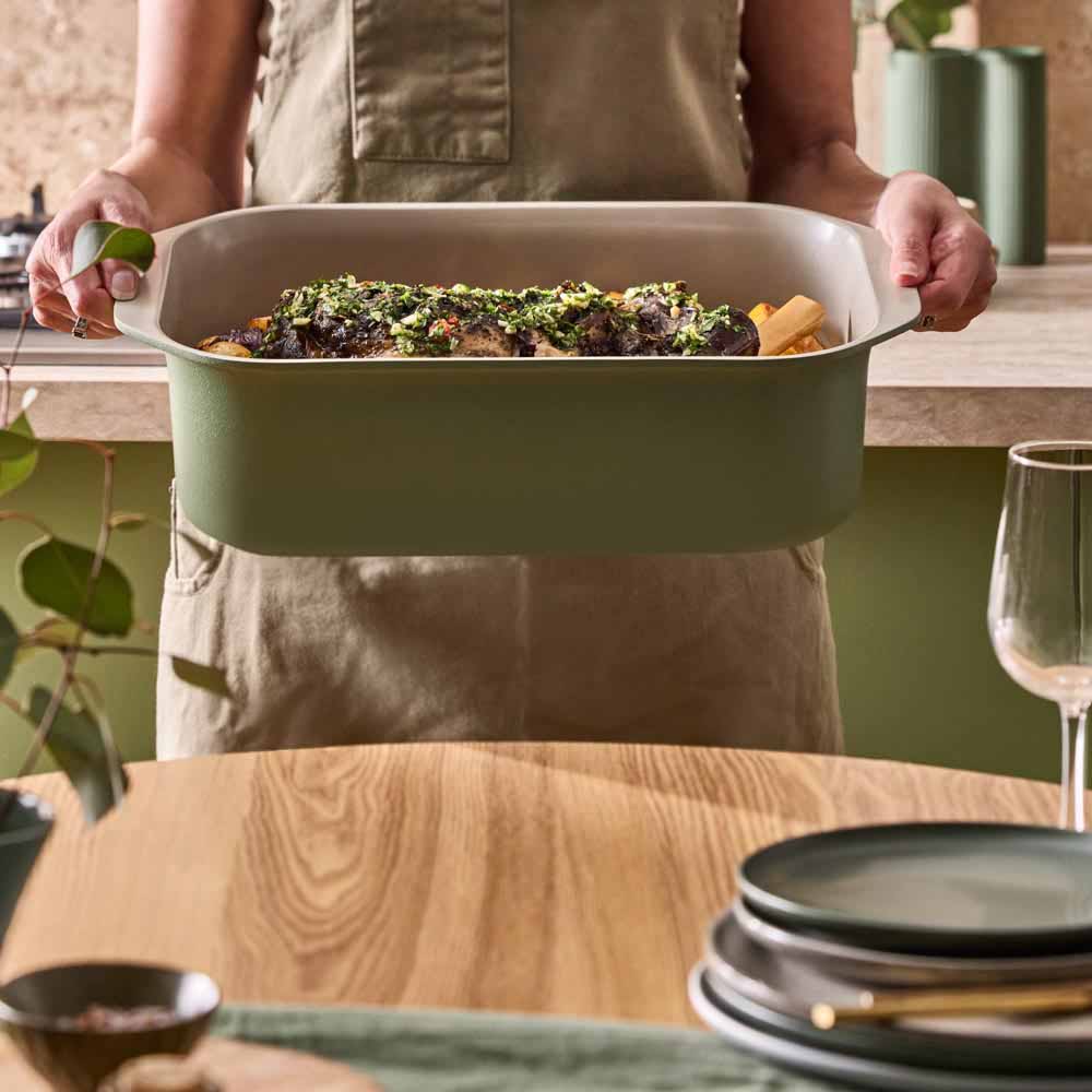 lamb shank and vegetables in a green roasting pan