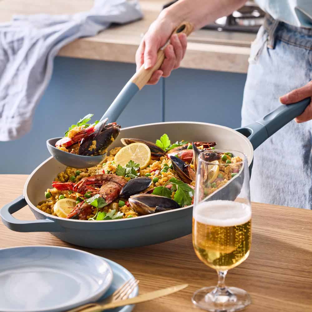 seafood paella served from a blue frypan on the dining table