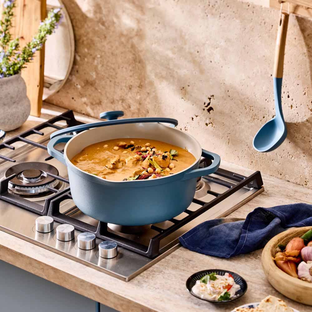 red dahl cooking in a blue casserole pot on the stove