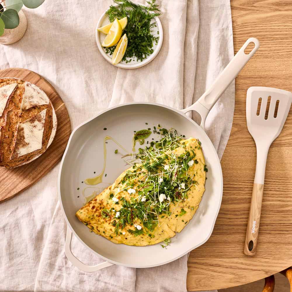 omelette served in cream frypan with cream utensil