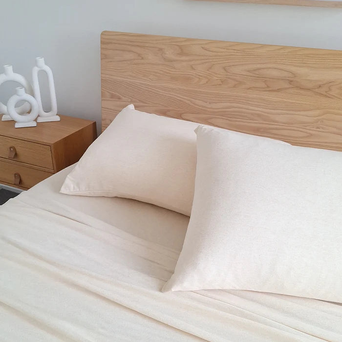 Beige bedding set on a bed with a wooden headboard and nightstand.
