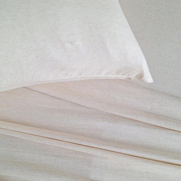 Close-up of beige bedding with a pillow on a neutral background