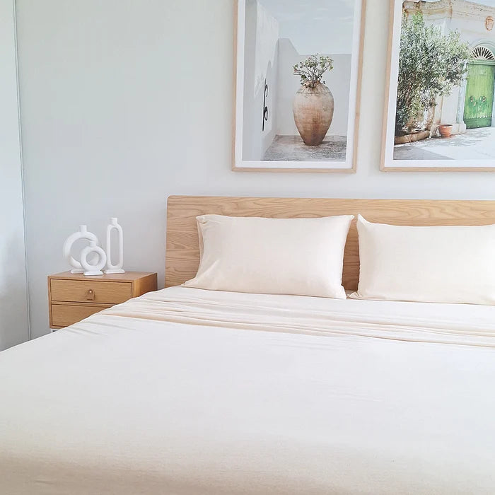 Bedroom with a wooden bed and white bedding, nightstand, and framed pictures on the wall.