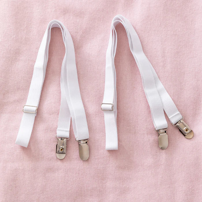 White suspenders with gold clips on a pink background