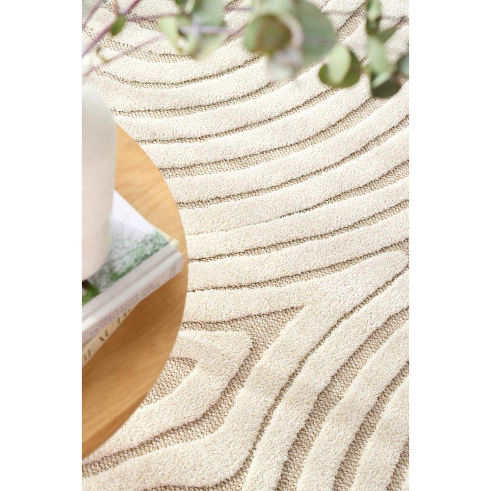 Natural beige swirl rug with side table, books, and vase - House