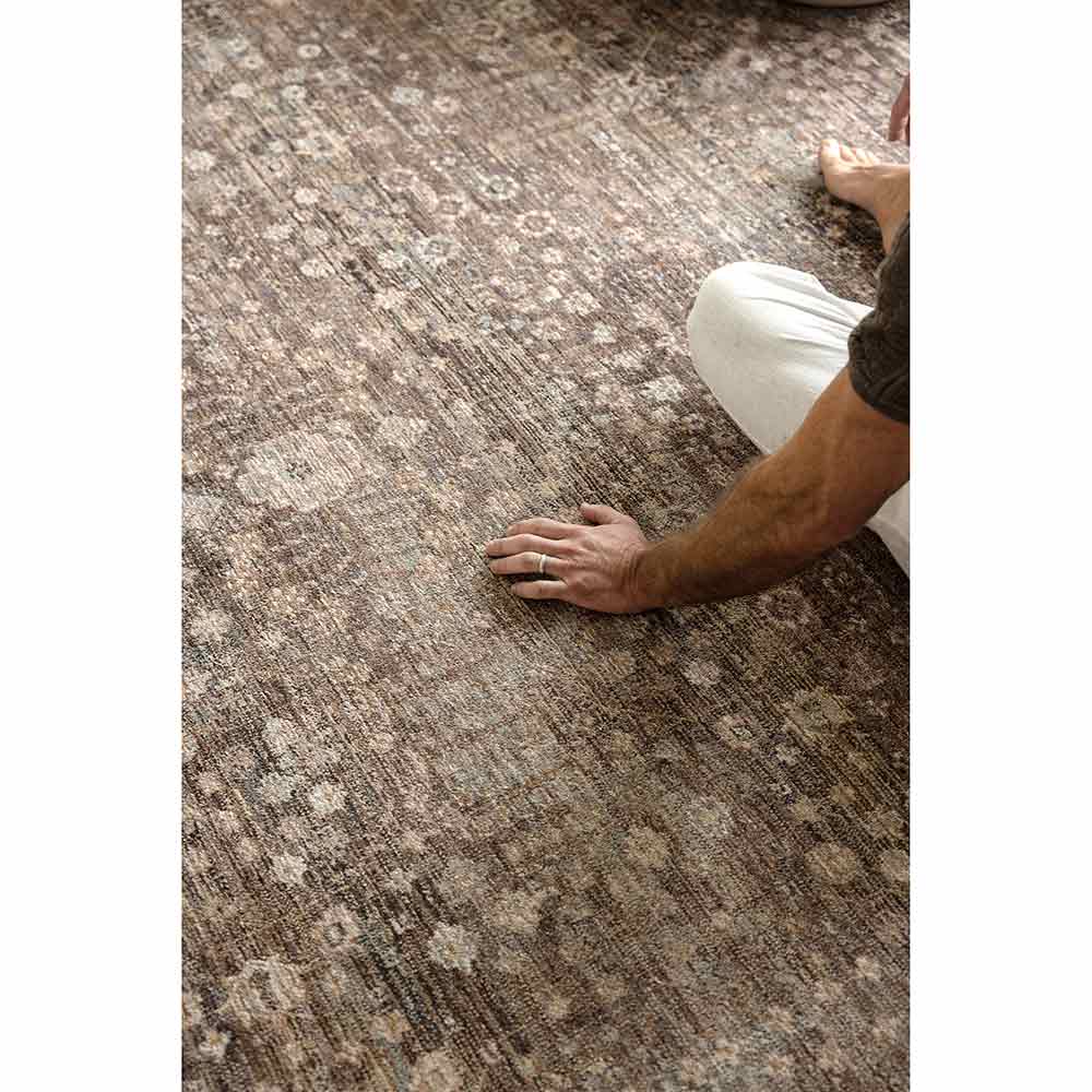 Darren Palmer Moorland Rug in Fig with Darren Palmer sitting on a rug at House