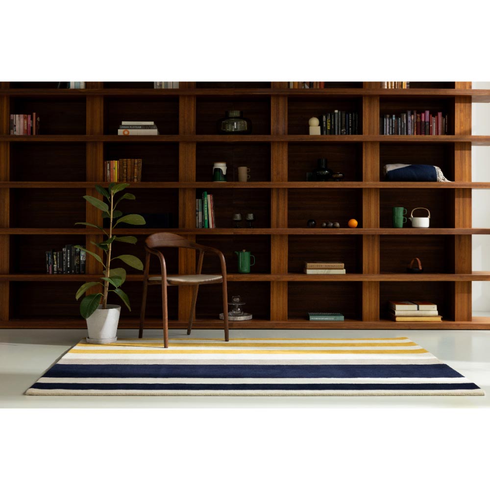 Marimekko Ralli Rug Yellow. Yellow and blue stripe rug in front of a bookcase