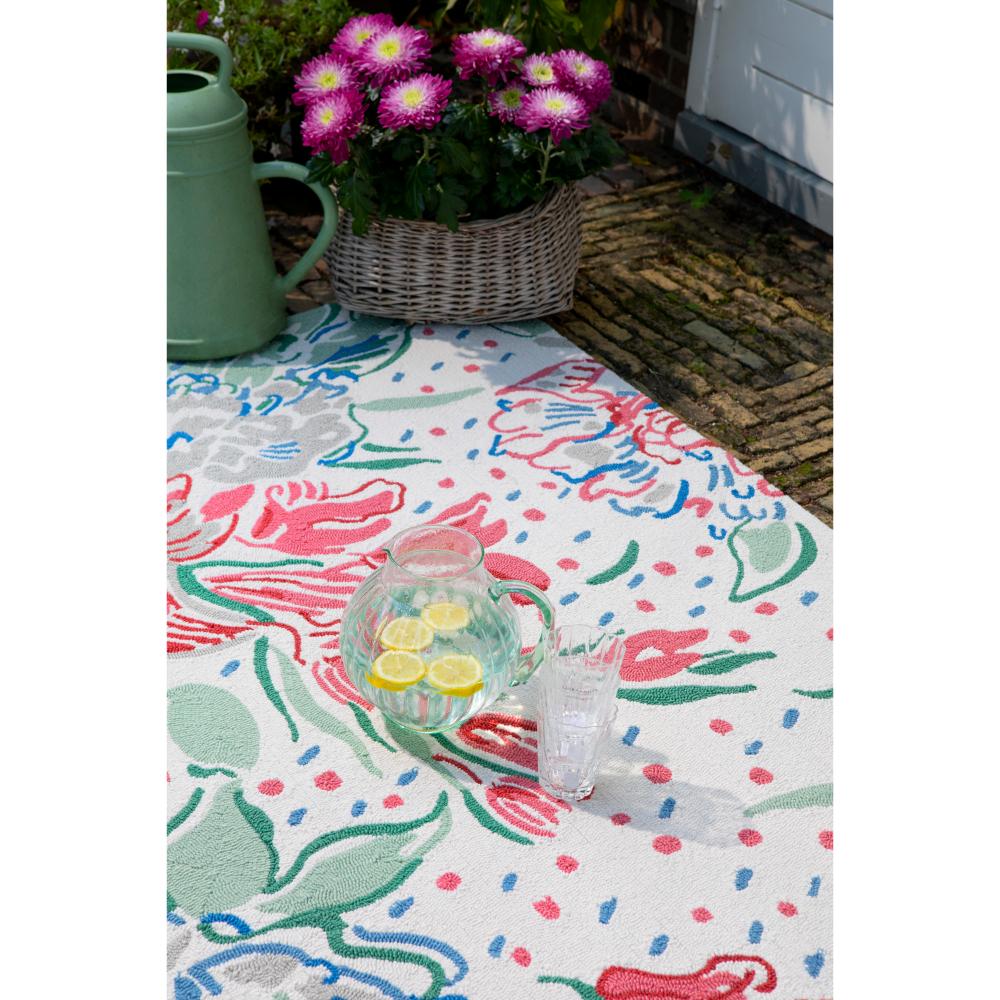 floral indoor/outdoor rug in backyard with a a jug of water - House