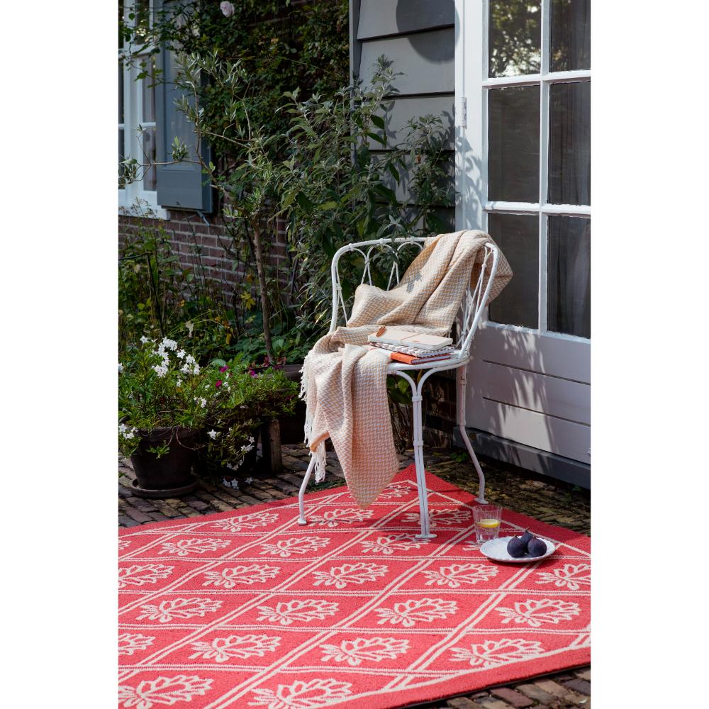 red floral outdoor rug in backyard with chair and throw - House
